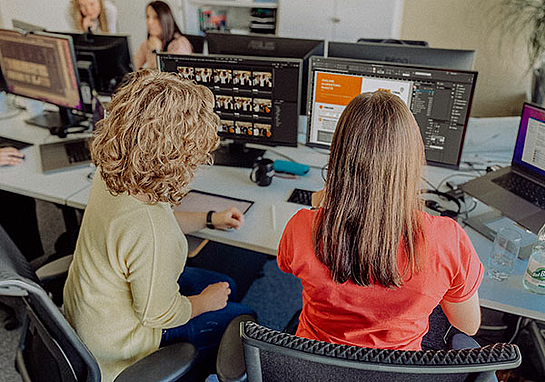 Zwei Frauen arbeiten am PC mit Photoshop und gestalten ein Banner