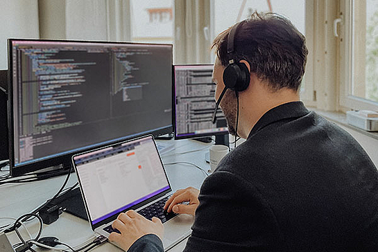 Entwickler in Ebern sitzt vor einem Bildschirm mit Codezeilen